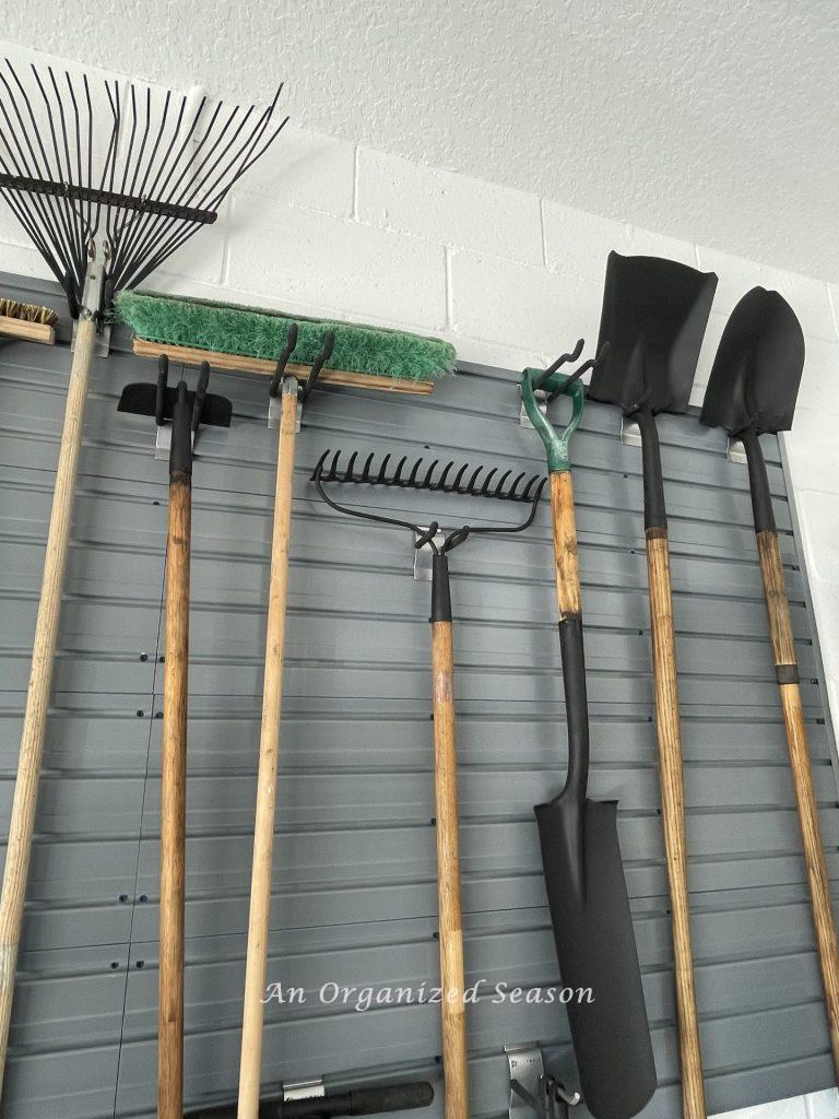 Lawn tools organized on a garage wall.