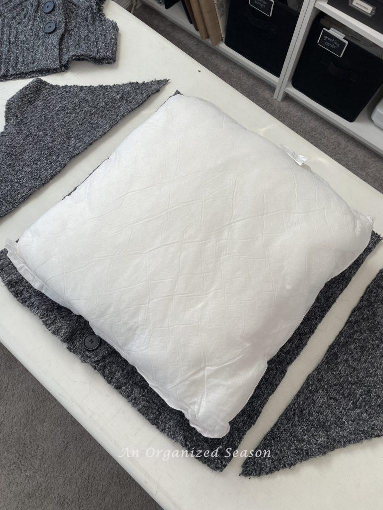 Someone cut a sweater to the size of a pillow insert, step two for how to make cozy home decor with sweaters.