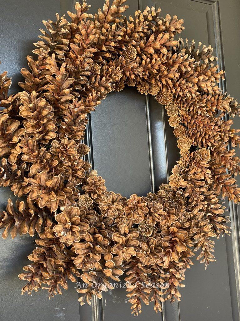 A pinecone wreath on a black front door. 