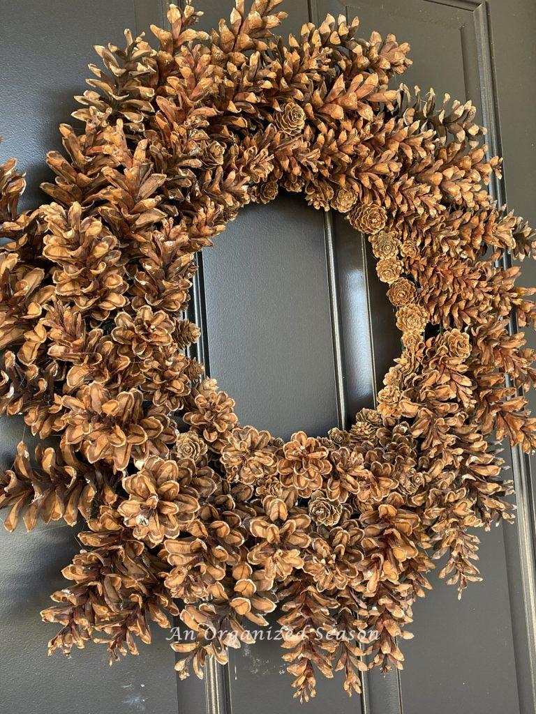 A pinecone wreath on a black front door.