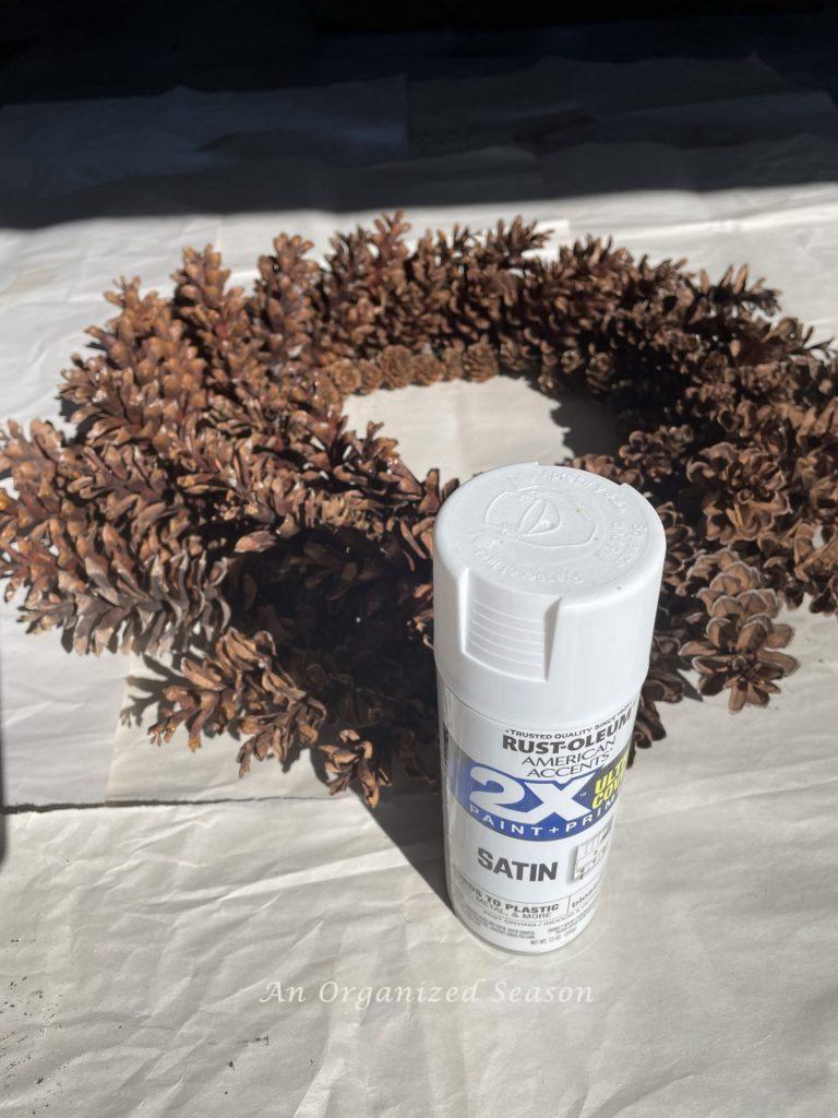 A pinecone wreath with a can of spray paint in front of it.