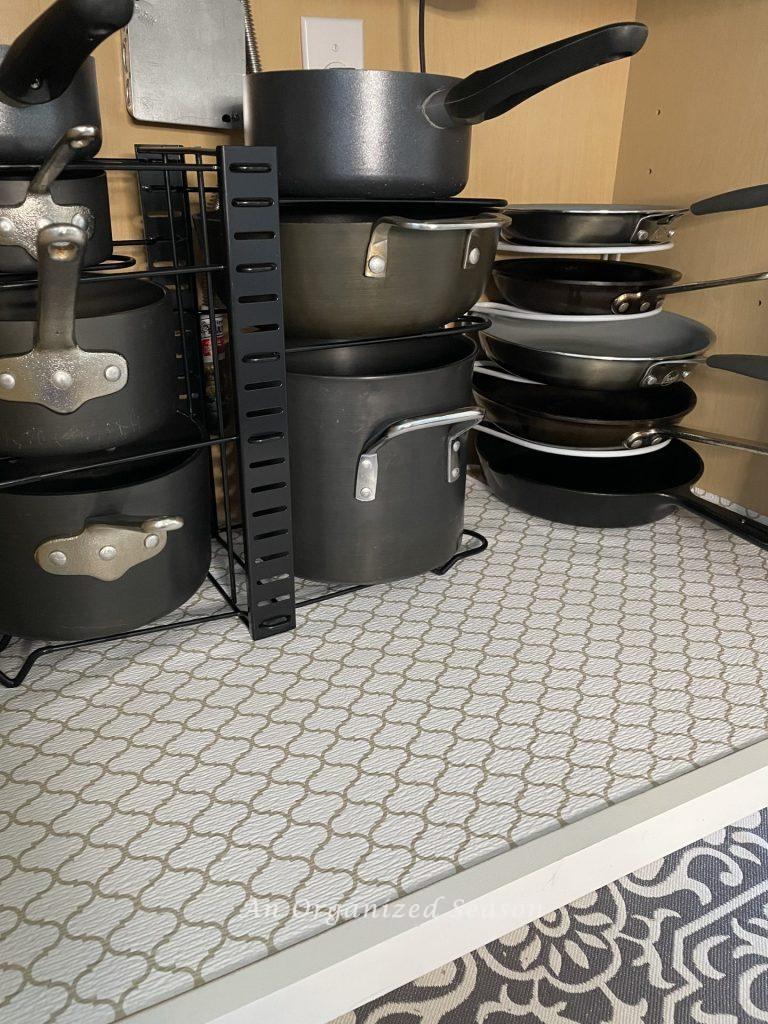 Pots and pans stacked on wire kitchen organizers. 