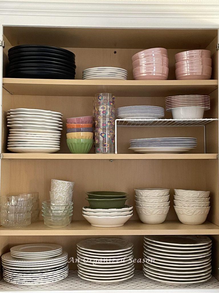 Organized plates and bowls in a kitchen cabinet. 