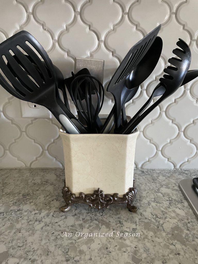 Cooking utensils stored in a beautiful canister helps to declutter and decorate kitchen counters.