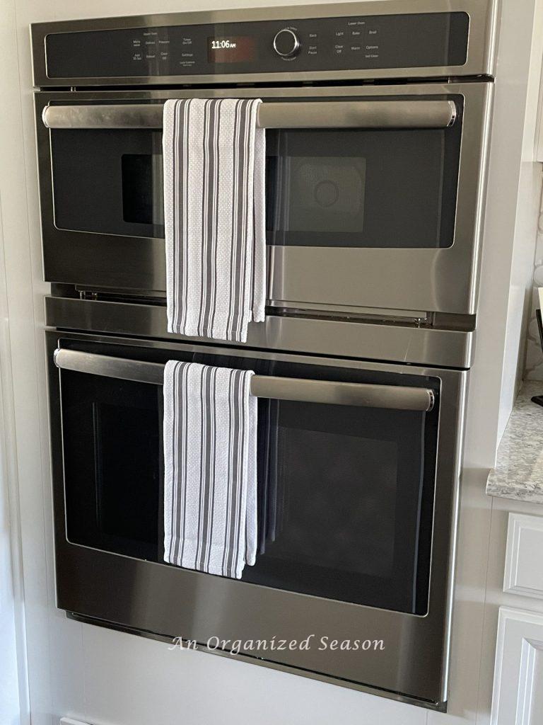A microwave and oven with dish towels hanging on handles. 