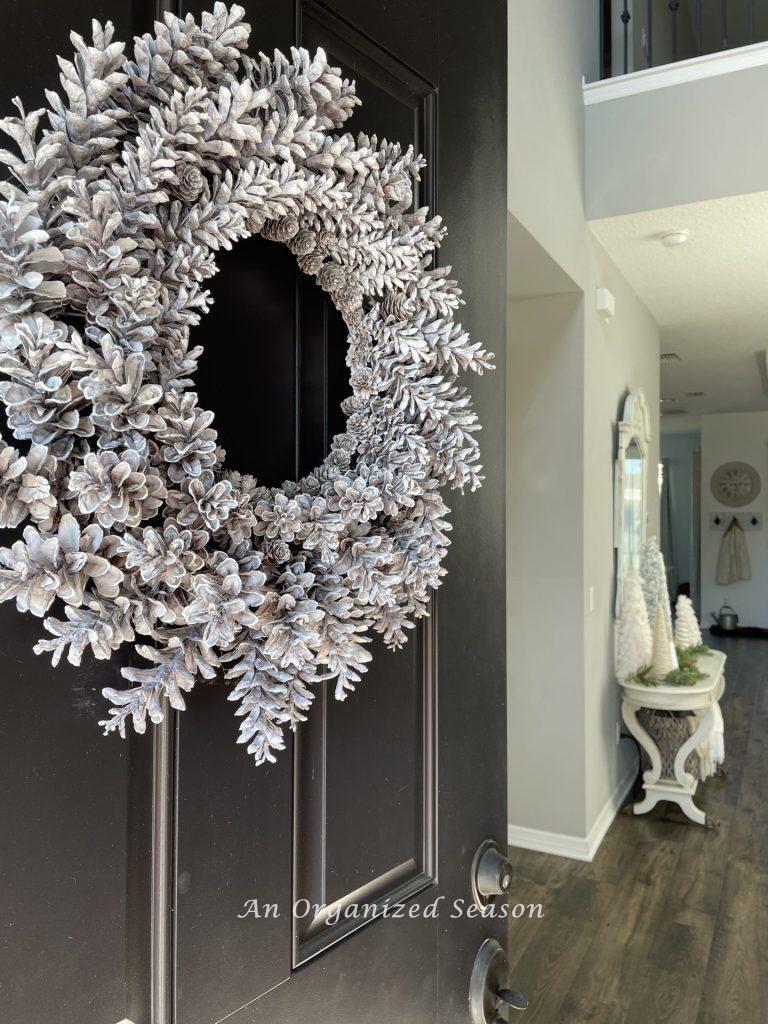 A white pinecone wreath on a front door is an example of  Winter decor ideas that don't look like Christmas!