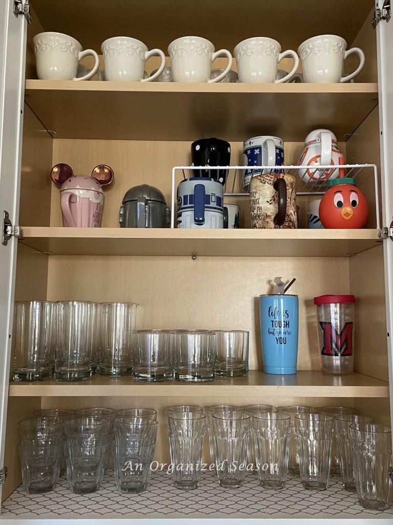 Organized glasses and cups in a kitchen cabinet. 