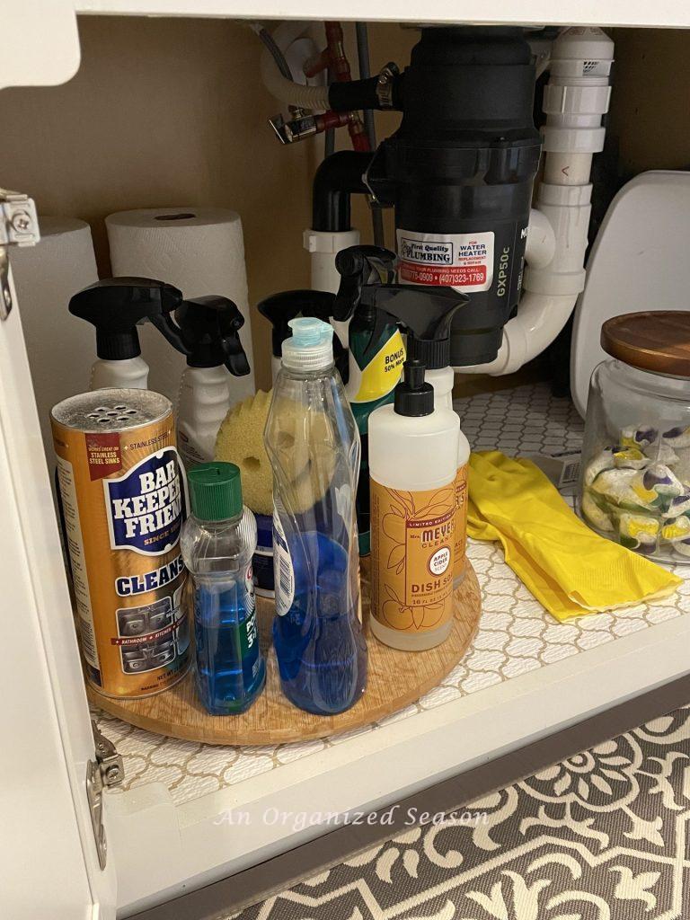 A lazy Susan holding cleaning supplies in a kitchen cabinet! 