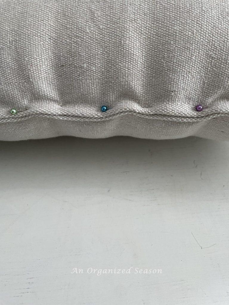 A drop cloth pillow with the end pinned together, 