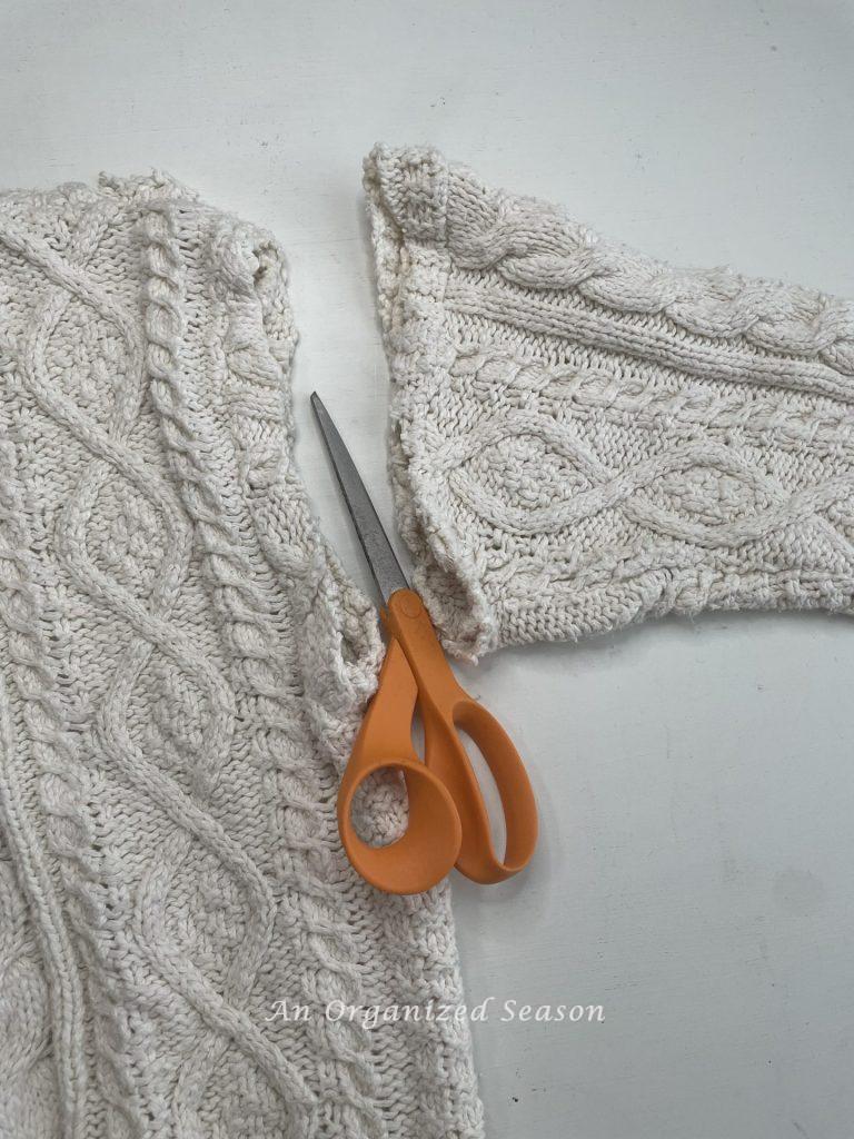 A sweater with the arm cut off, step one for how to make cozy home decor with sweaters.