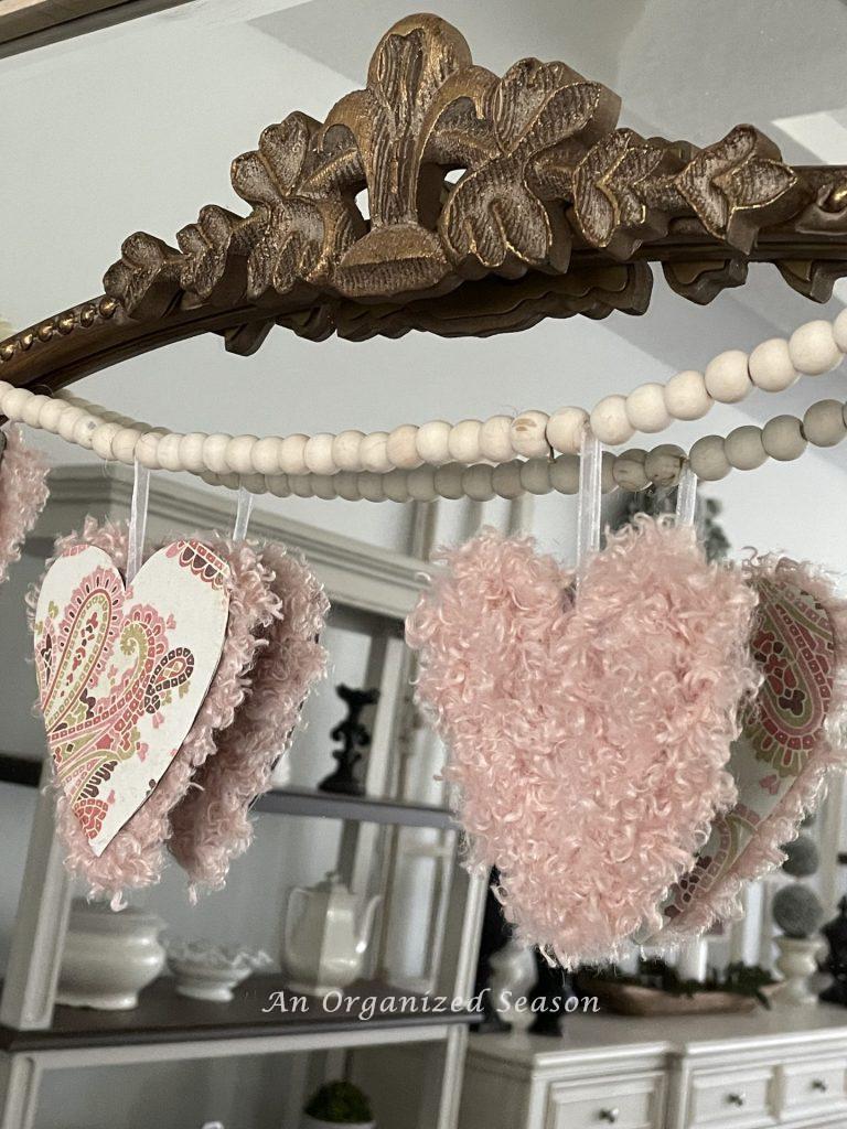 A wood bead garland with Valentine's hearts draped on a mirror. 