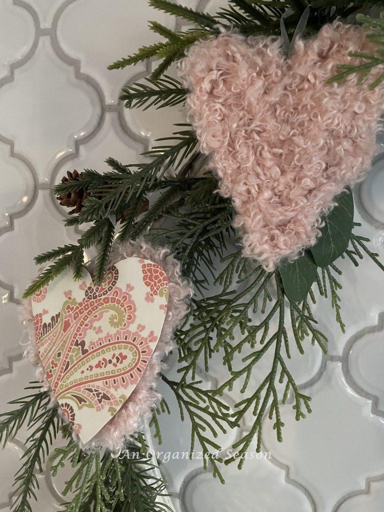 Two Valentine's hearts hanging on a wreath.