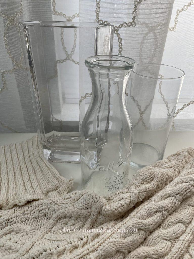 Three glass vases and a cream cable knit sweater.