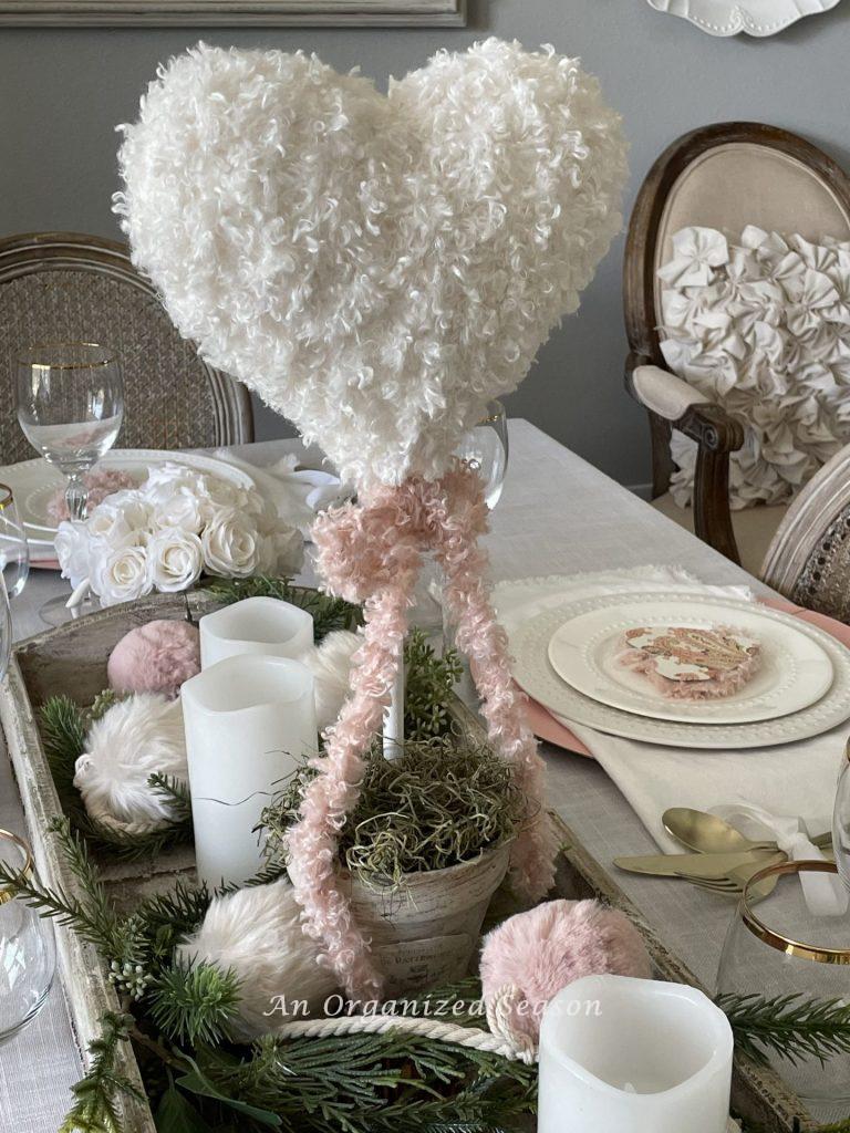 A heart topiary centerpiece on a dining table. 