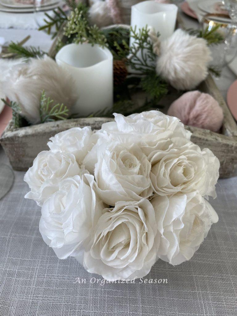 White roses in a small bowl set on a table decorated for Galentine's day.