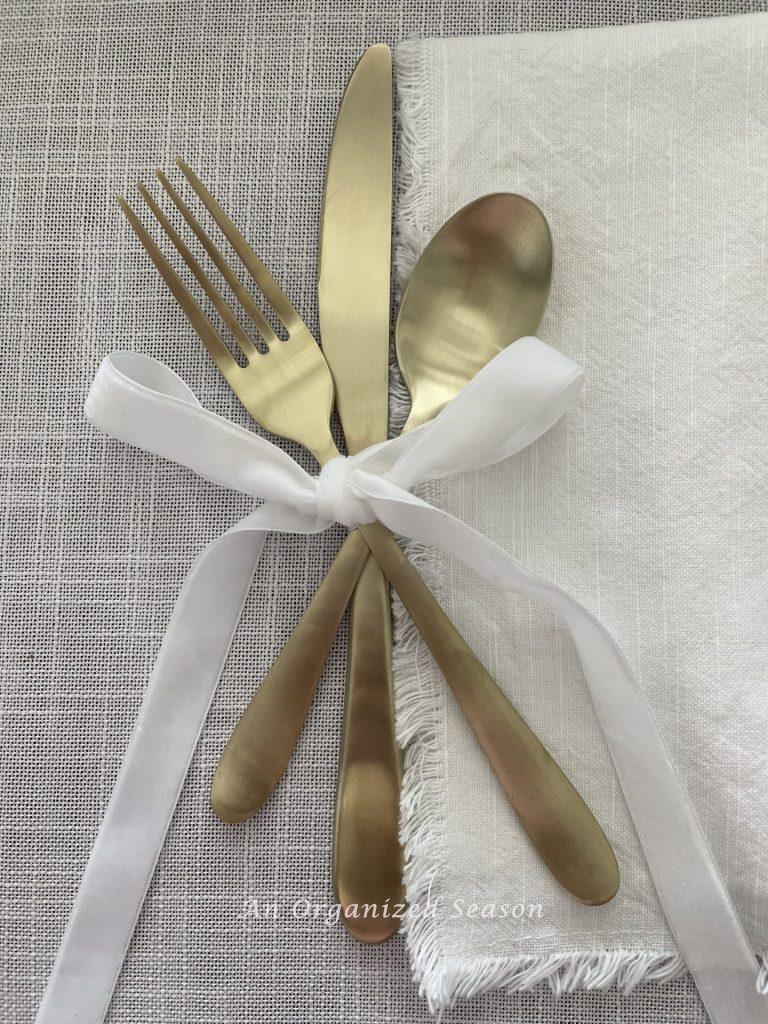 Gold eating utensils with a velvet bow  set on a table decorated for Galentine's day. 