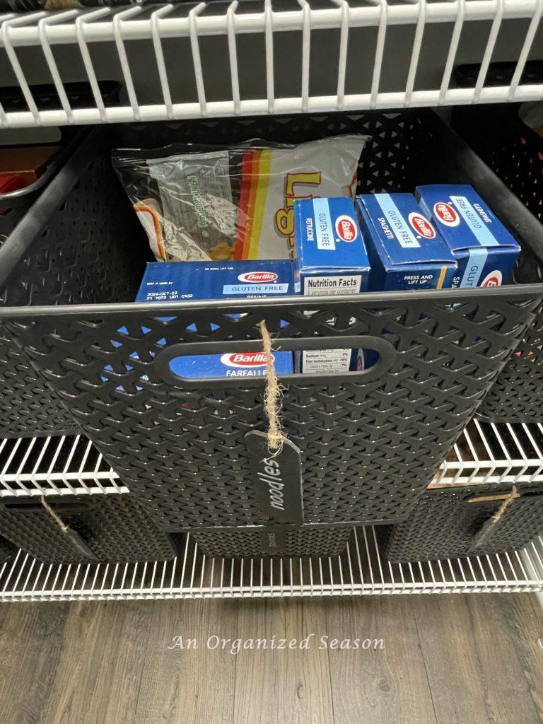 Noodles stored in a black plastic bin on a pantry shelf. 