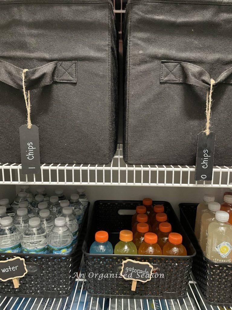 Chips and water organized in a pantry with black bins. 