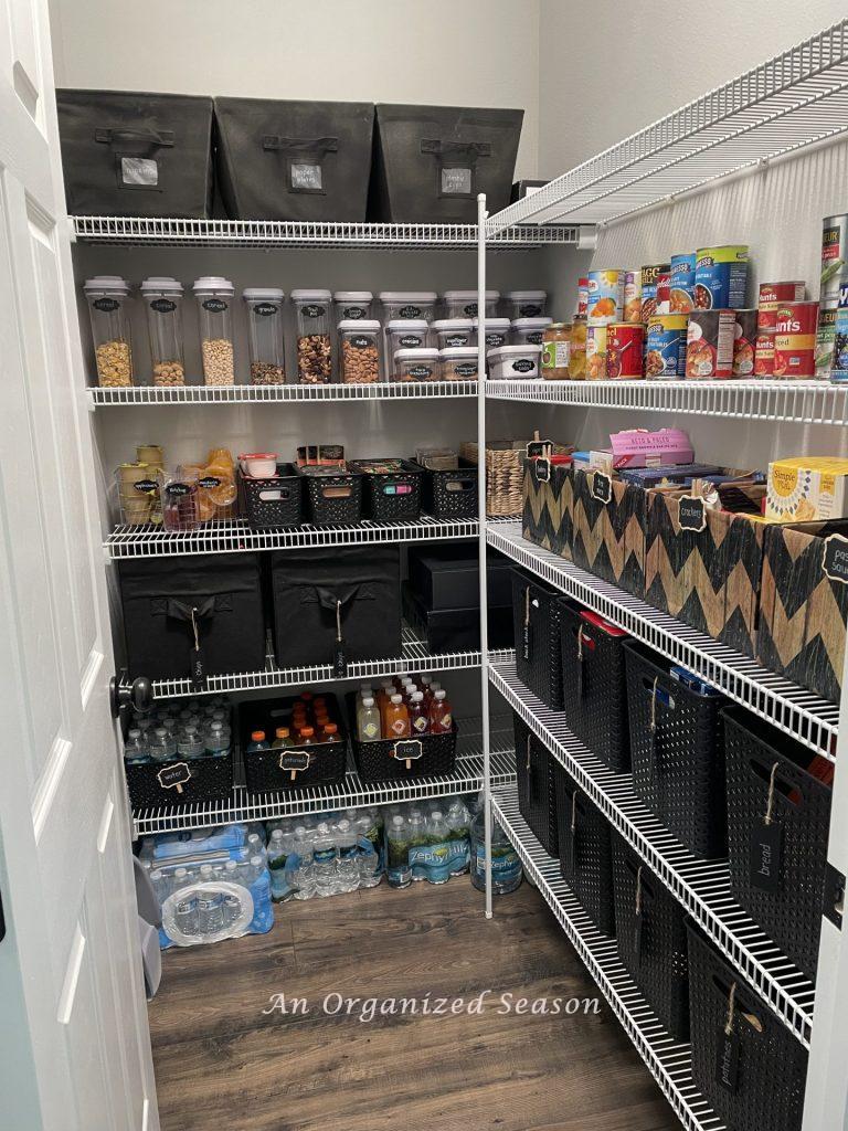 A pantry organized with Oxo containers and black bins. 