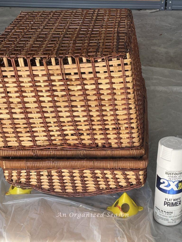 Step two to upcycle a picnic basket is to  turn it upside down and prime it. with spray primer.