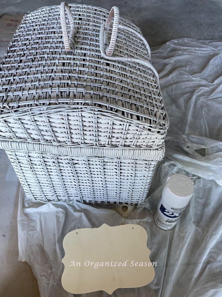 Step four to upcycle a picnic basket is to prime a wood sign.