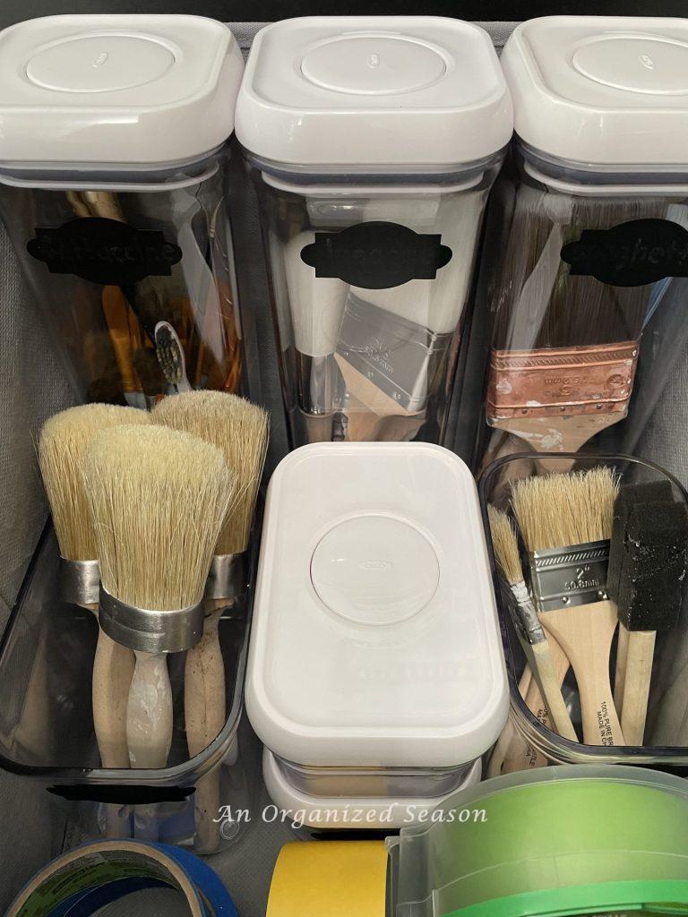 Organize must-have craft supplies by storing all of your paint brushes in plastic containers inside a fabric storage cube.