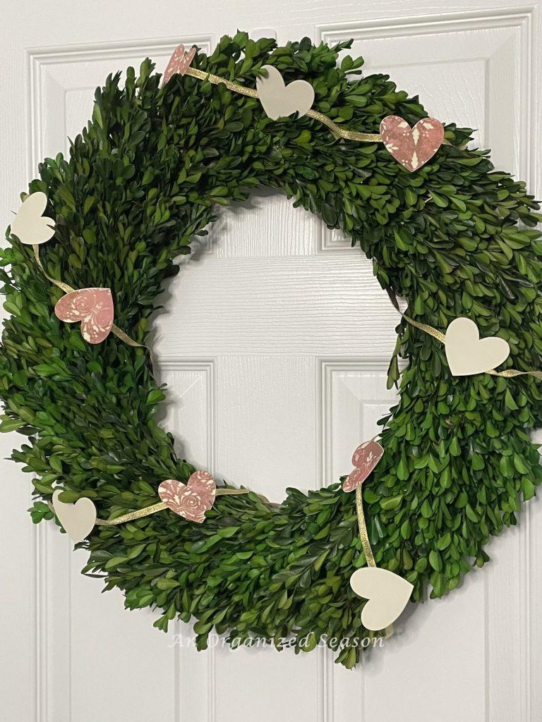 Box wood wreath wrapped with a heart garland. 