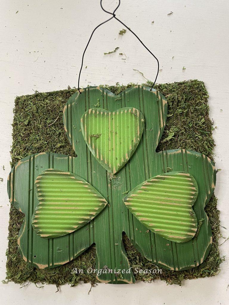 Step two in a DIY St. Patrick's makeover is to lay the sign on moss and cut out around it. 