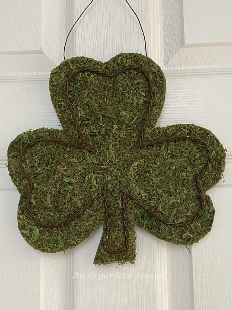 A moss shamrock hanging on a door. 