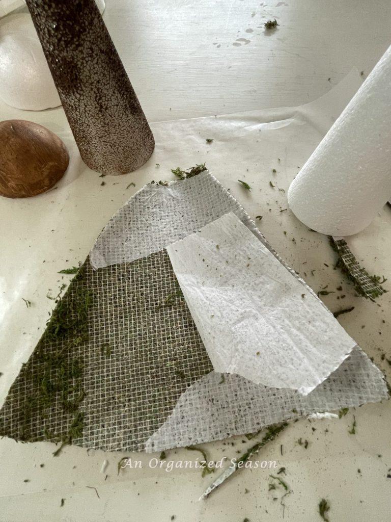 Paper backing being peeled off a moss mat used to make moss mushroom home decor.