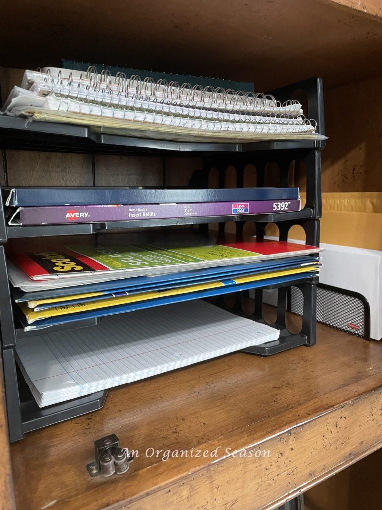 Using stackable trays in a cabinet is a brilliant way to organize office supplies.