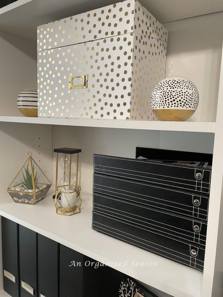 Use stackable trays and decorative storage boxes on a shelf.