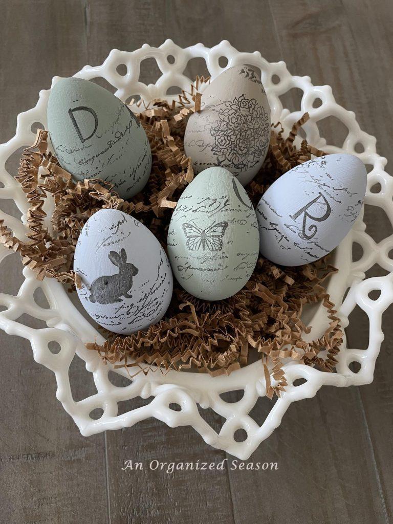 Five painted and stamped eggs in a white bowl.