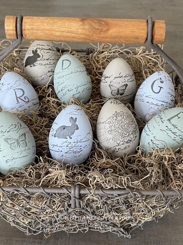 Painted and stamped eggs in a wire basket with moss.