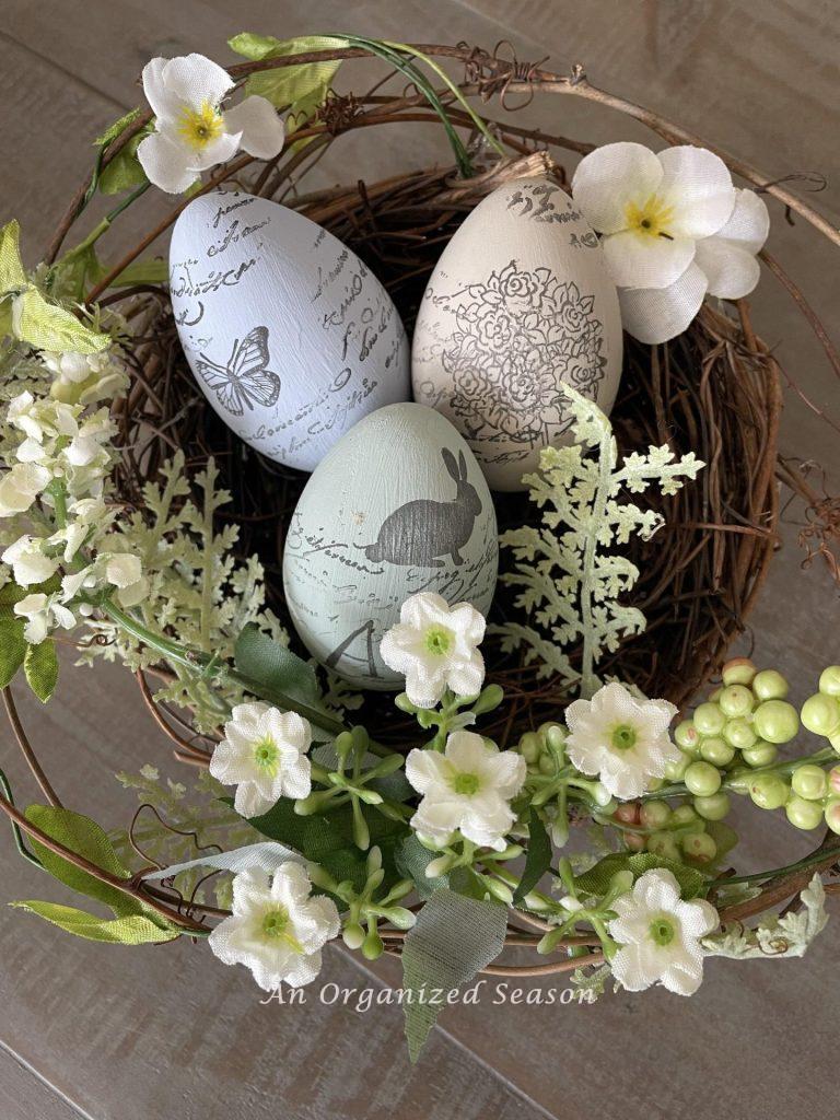 Three painted and stamped eggs displayed in a bird nest. 
