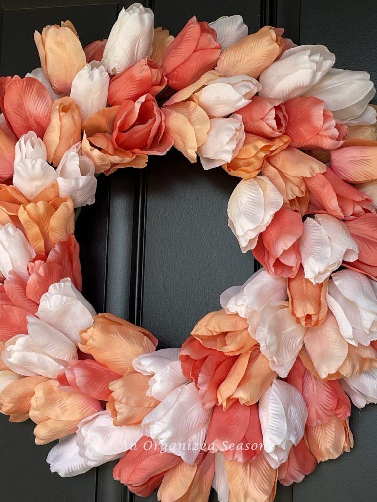 A tulip wreath hanging on a black door. 