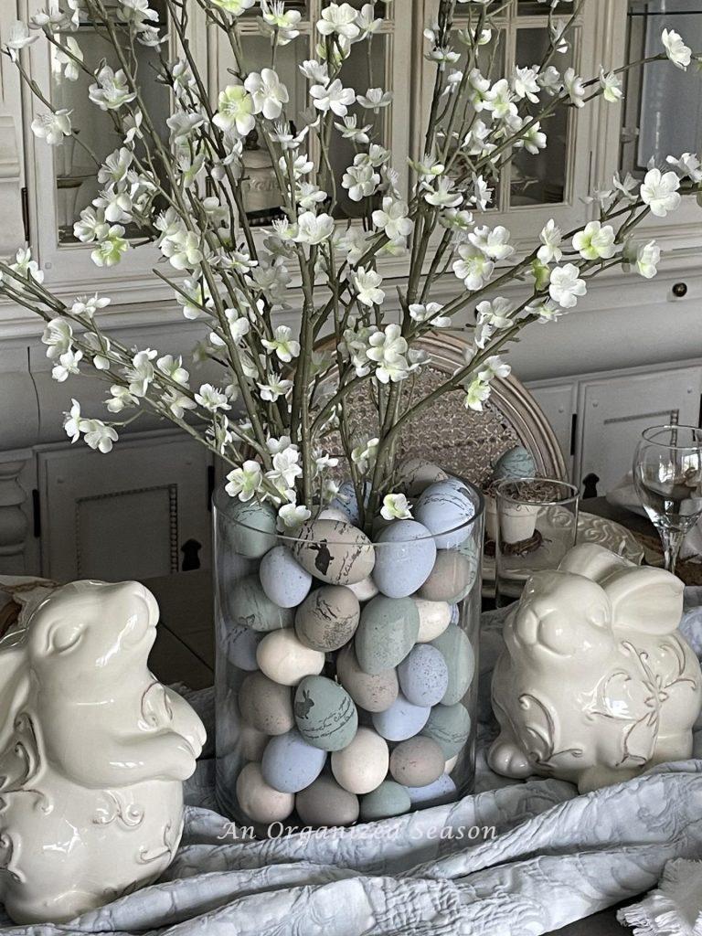 A centerpiece of flowering branches in a glass vase filled with colored eggs makes great Easter table decor.