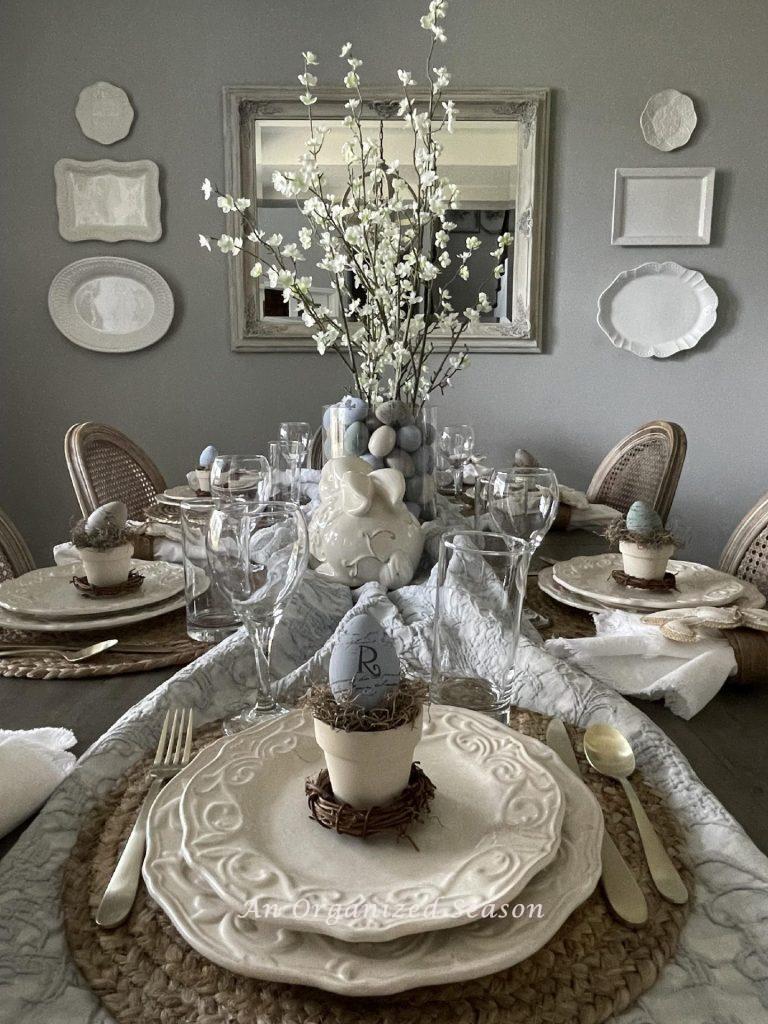 A table decorated for Easter with flowering branches, bunnies, and nests. 