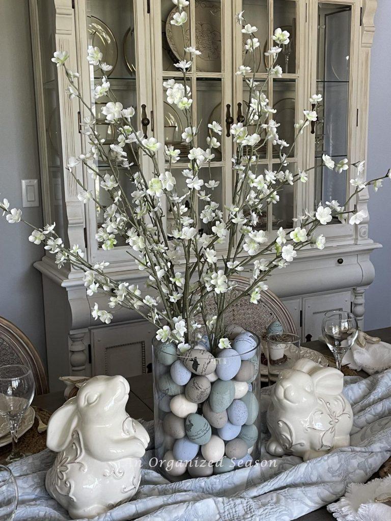 An Easter centerpiece of flowering branches and two bunnies. 