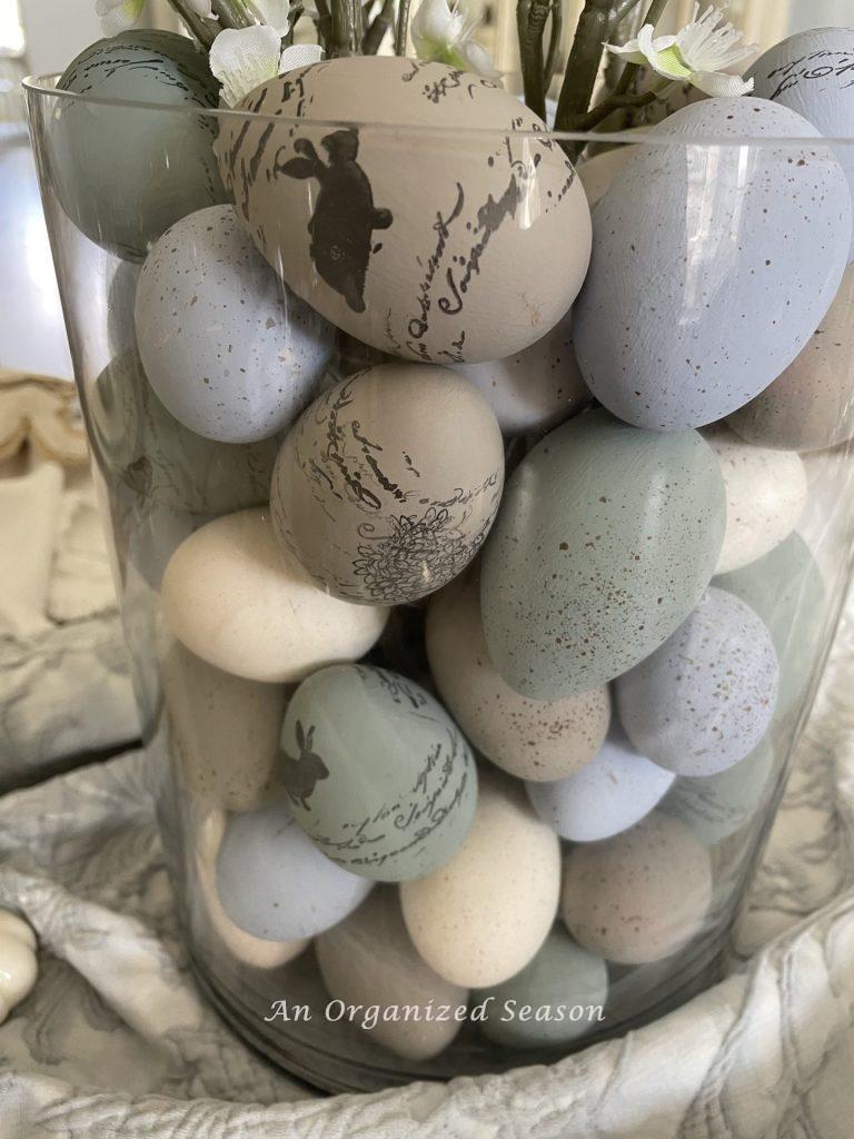 Colored Easter eggs inside a large glass vase. 