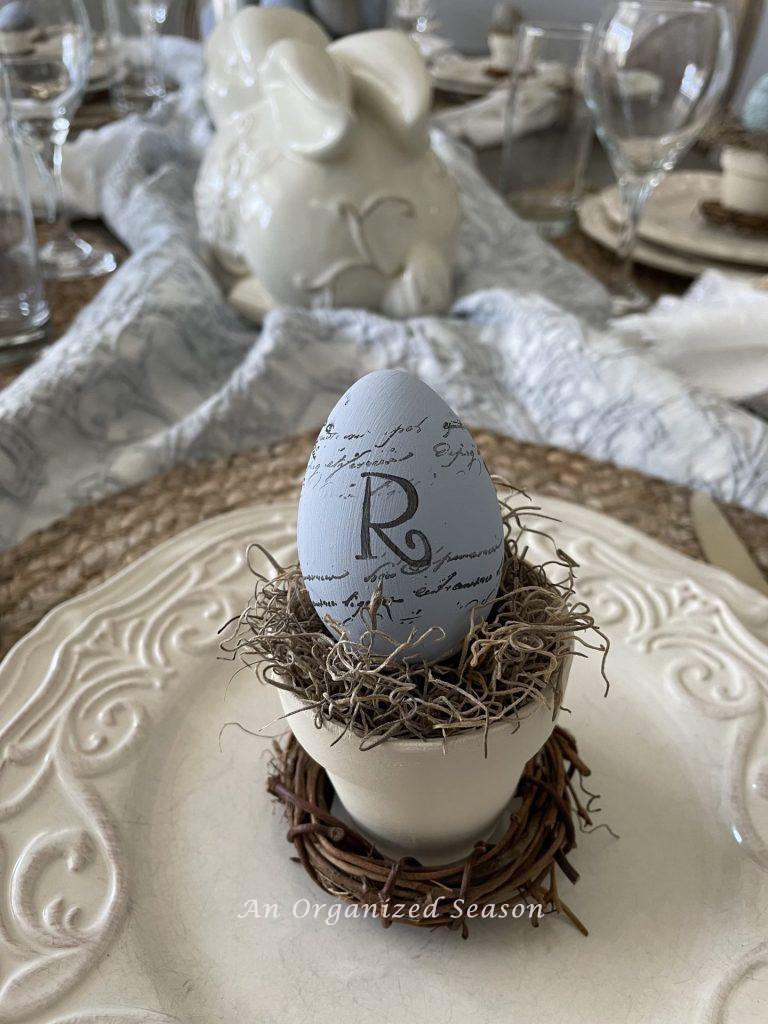 An egg with the initial "R" inside a mini flower pot. 
