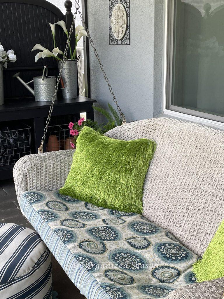 A white wicker swing on a back porch. 