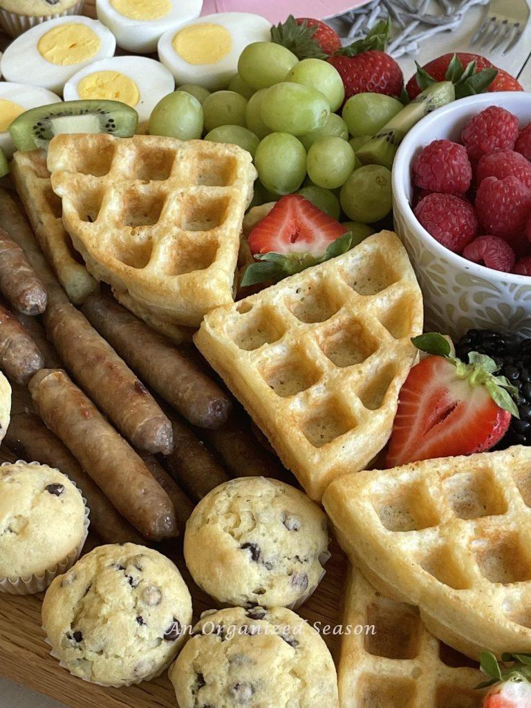 Sausage links, fruit, waffles, and eggs. 