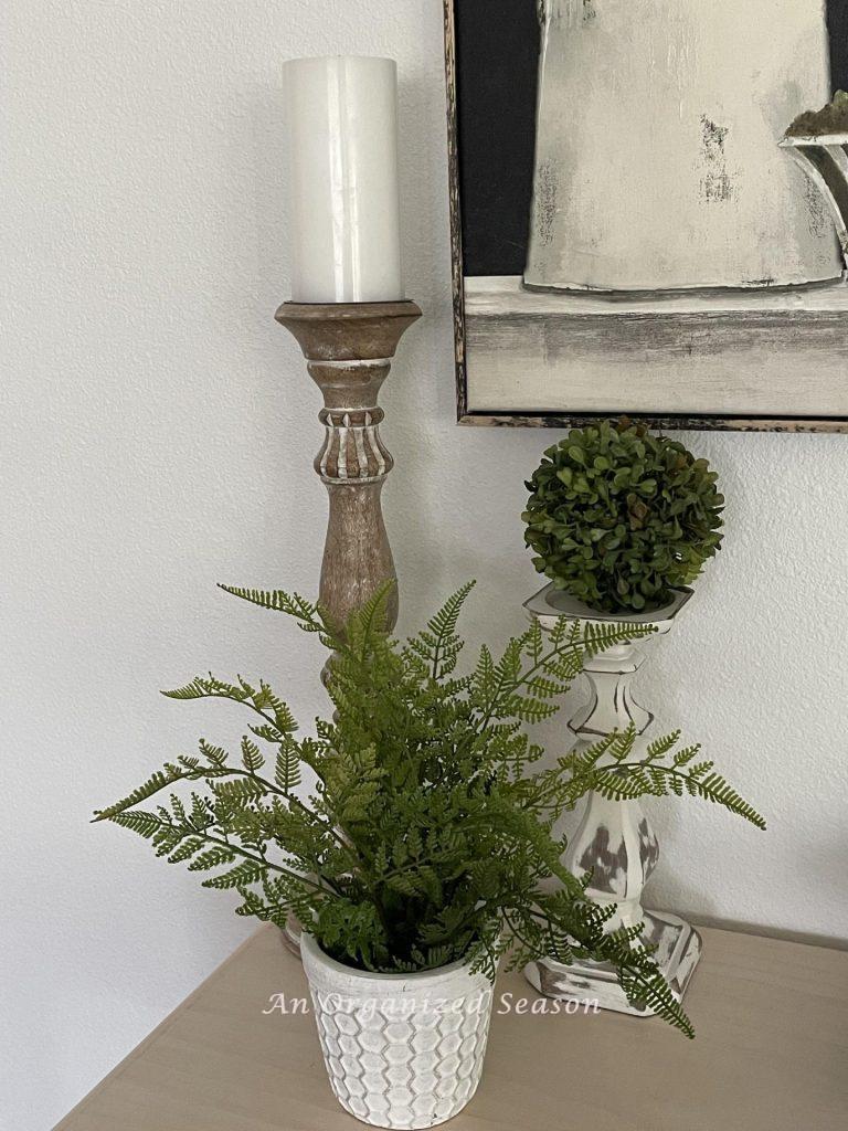 A potted fern in front of two candlesticks.