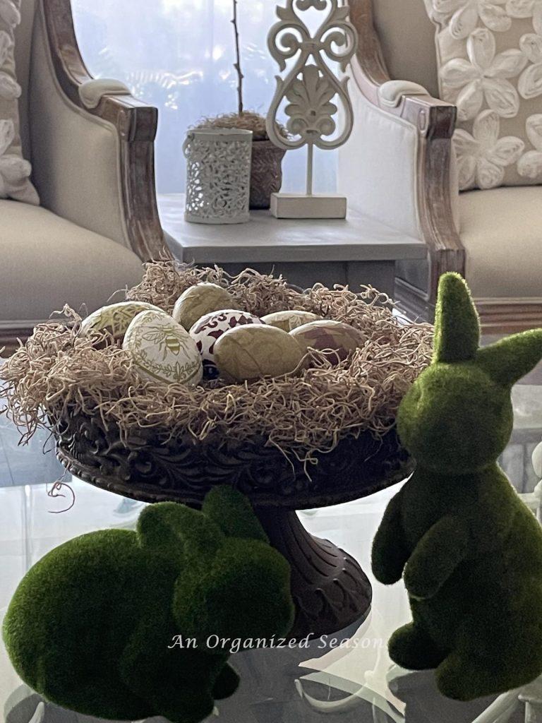 A good Spring decorating idea is to use moss bunnies and decoupaged eggs on a metal pedestal. 