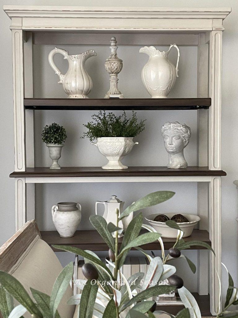 Bookshelves with white ironstone pitchers and bowls. 