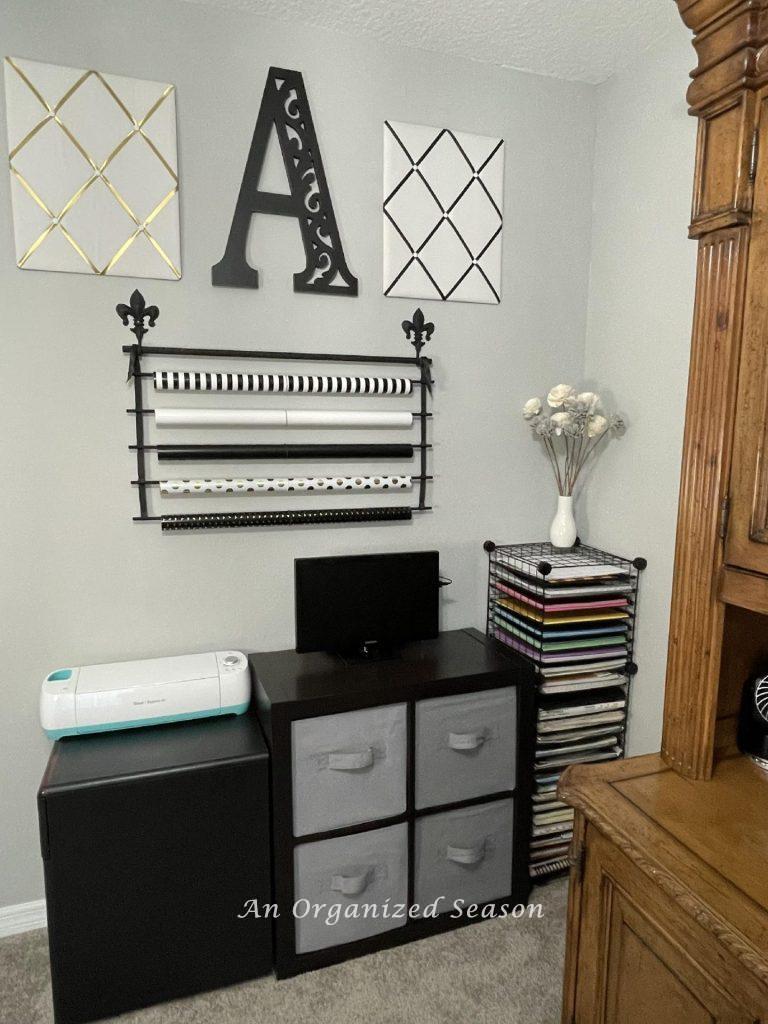 Cabinet, file, paper storage unit, small tv, with a gift paper organizer hanging over them. 