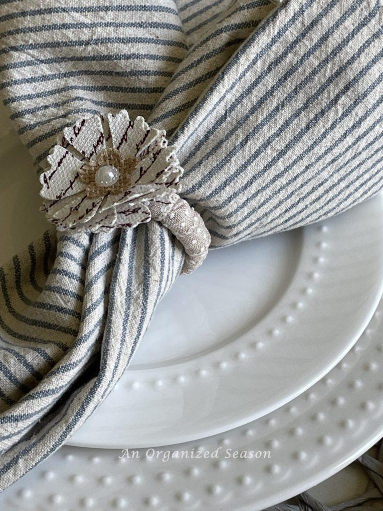 A floral napkin ring with a blue and cream striped napkin are a great decorating idea for Spring. 