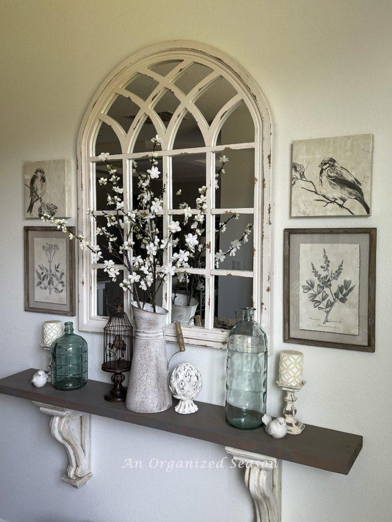 Mirror hanging over a shelf with corbels that's decorated for Spring. 