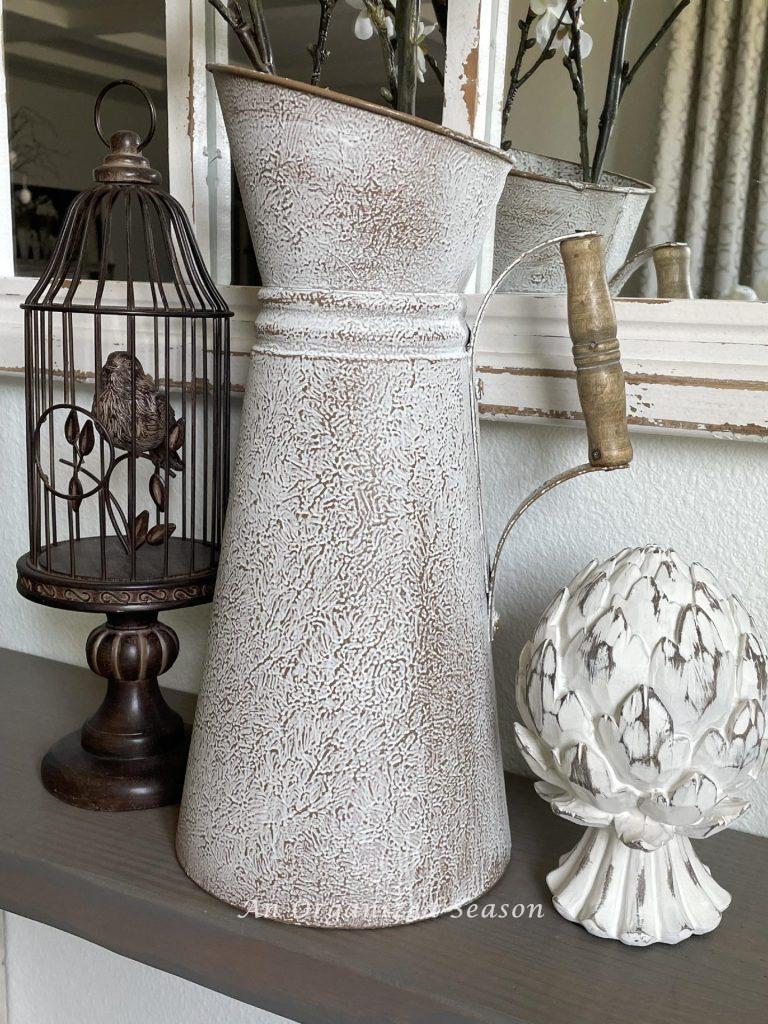 A birdcage, metal pitcher and artichoke statue are perfect Spring decorating ideas. 